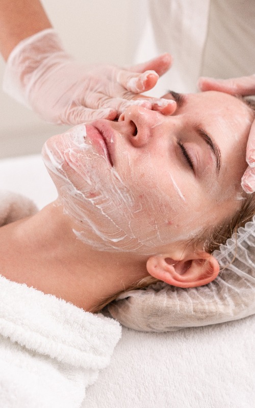 Der Arzt entfernt das Gel vom Gesicht des Patienten und trägt eine therapeutische Creme auf. Anti-Akne-Phototherapie. Schöne Frau während einer Fotoverjüngungsbehandlung. Behandlung der Gesichtshaut in einer Schönheitsklinik.