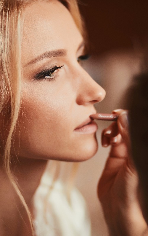 Visagist, der eine junge, schöne Braut schminkt und ihr Hochzeits-Make-up aufträgt