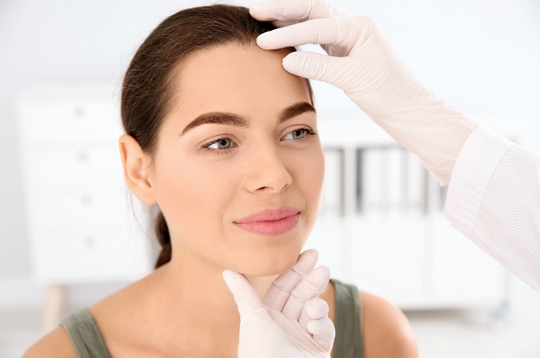 Ein Dermatologe untersucht das Gesicht eines Patienten in einer Praxis. Hautkrebsvorsorgeuntersuchung